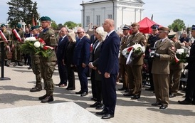 14. Przedstawiciele organizator&oacute;w składają kwiaty pod tablicą